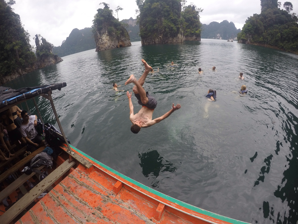 Person flipping into a lake with others swimming.