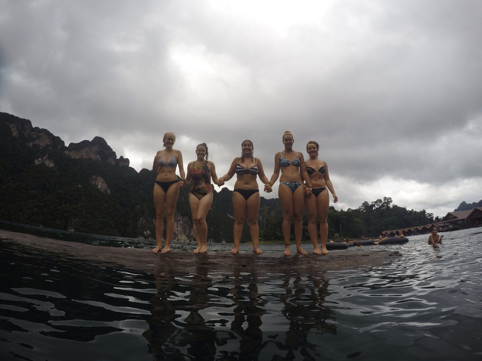 Group of women in swimsuits standing by the water.
