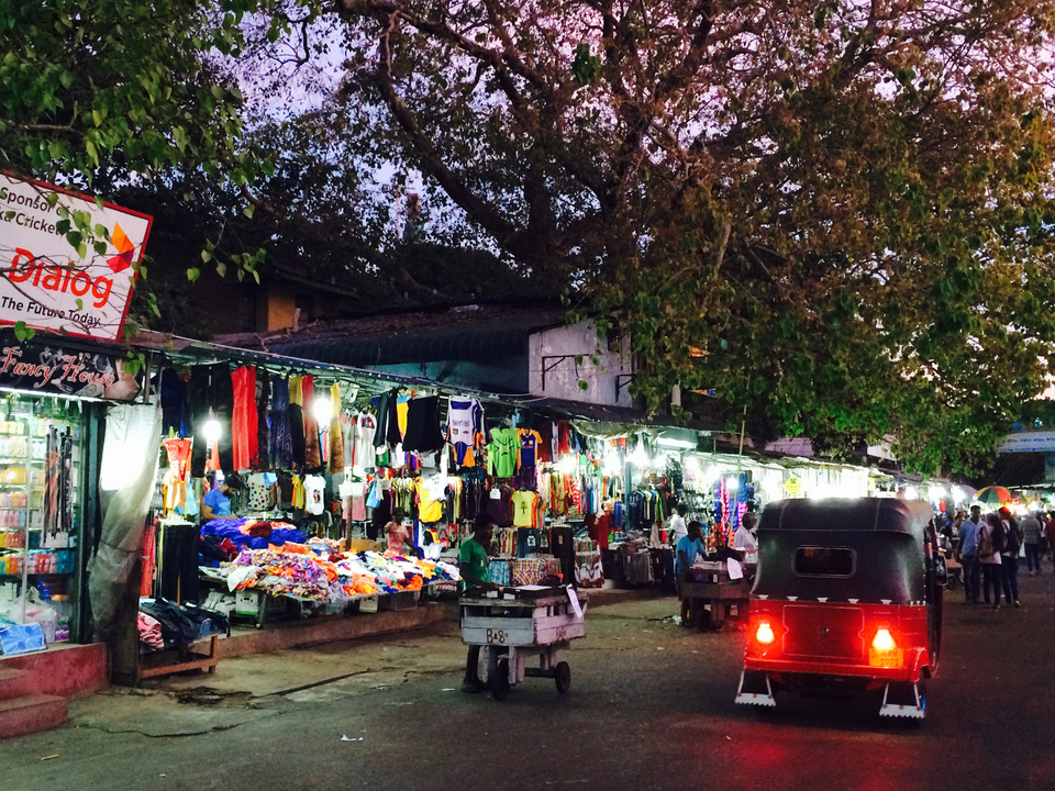 Marché avec des vêtements colorés et des gens autour.