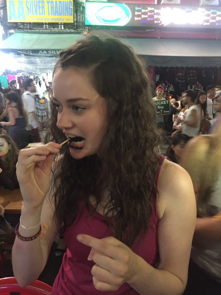 Woman eating food at a night market.