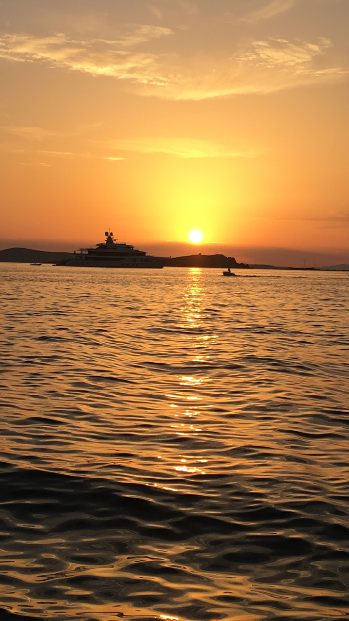 Yacht sur la mer au coucher du soleil avec une surface d'eau calme.