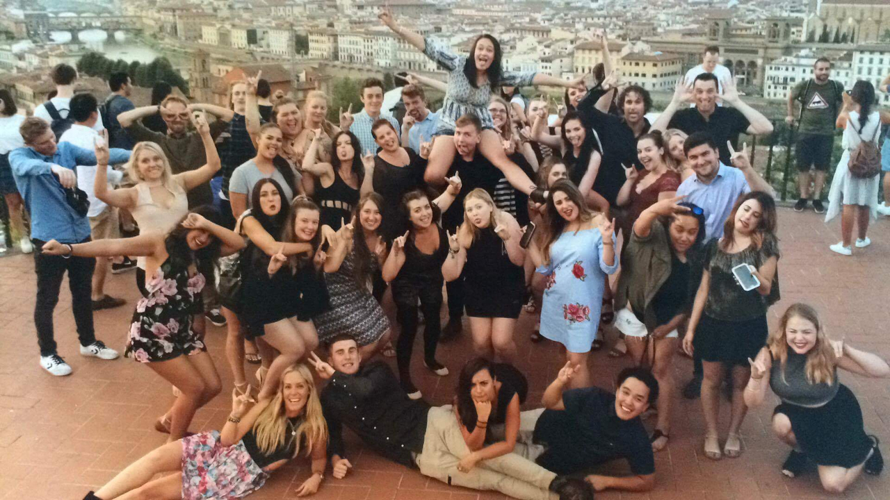 Grand groupe de personnes posant avec un paysage urbain en arrière-plan.