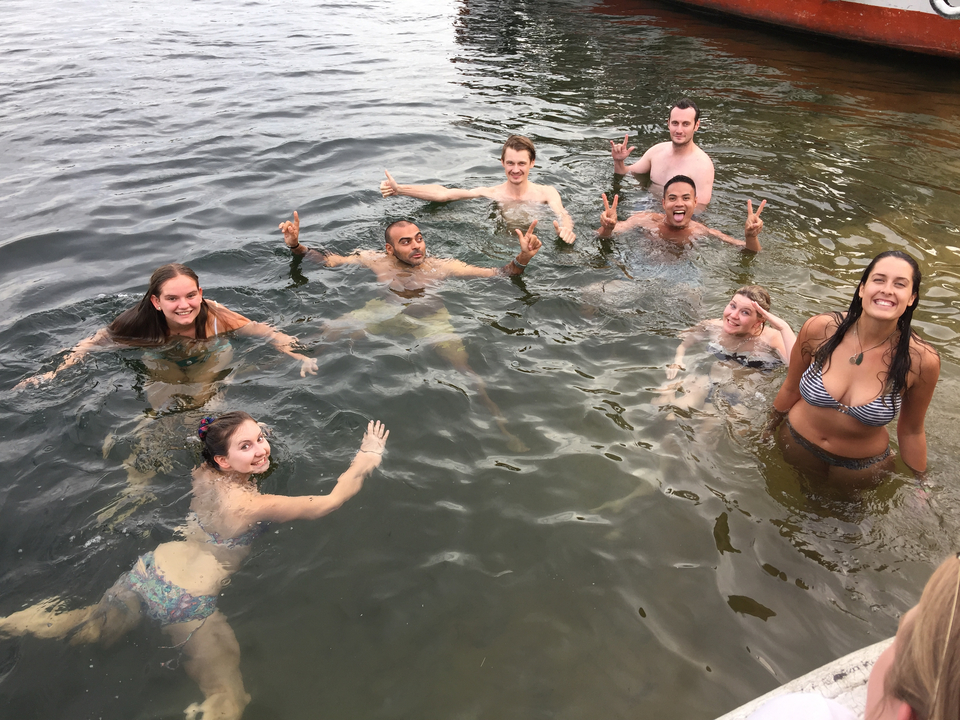 Groupe de personnes nageant dans l'eau, souriant à la caméra.