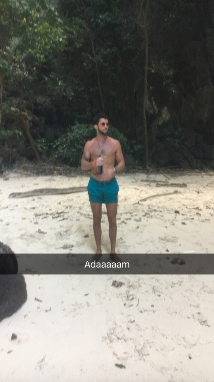 Blurry image of a person holding a drink on a beach.