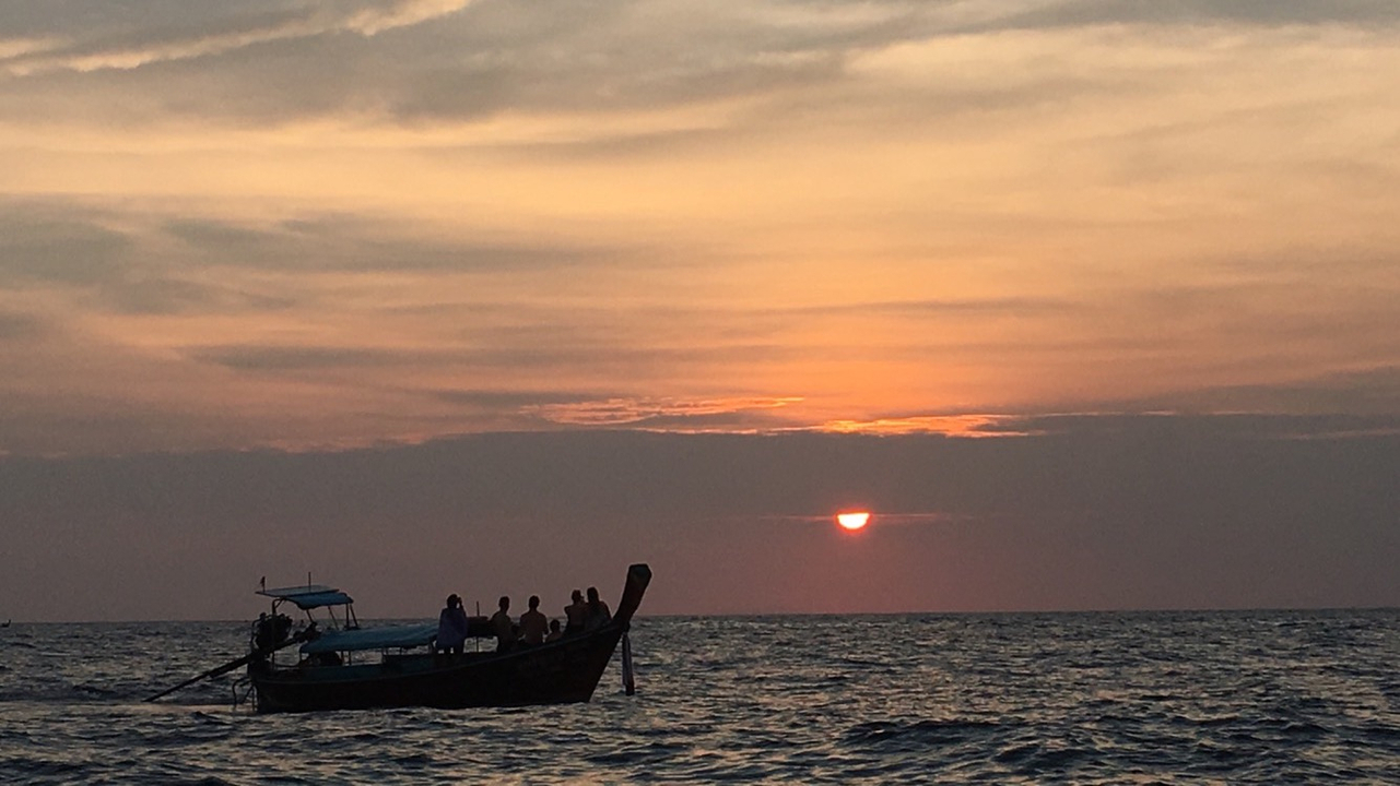 Boat silhouette against a sunset over the sea.