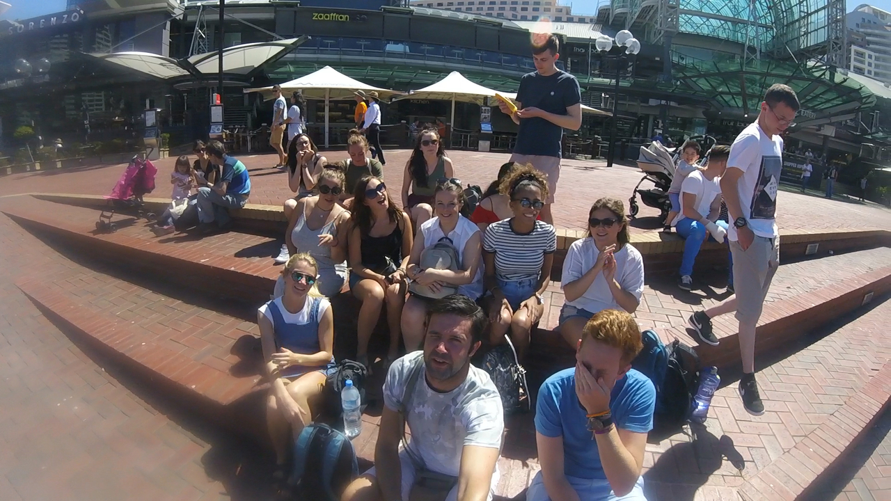 Group of people sitting on steps outdoors in a public area.