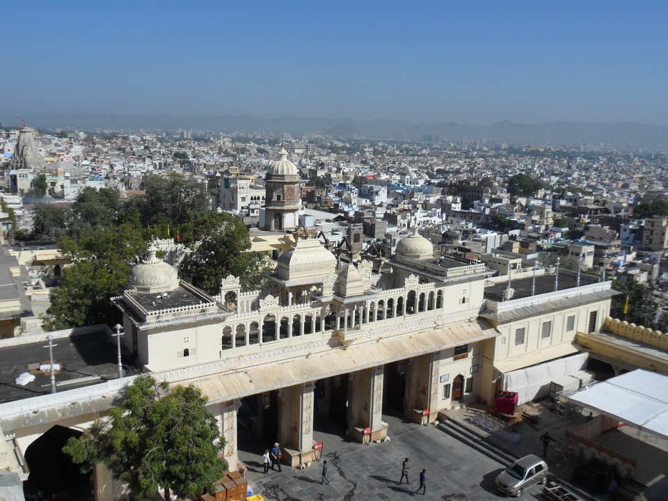 Aerial view of a sprawling Indian city with ornate palace roofs in foreground.