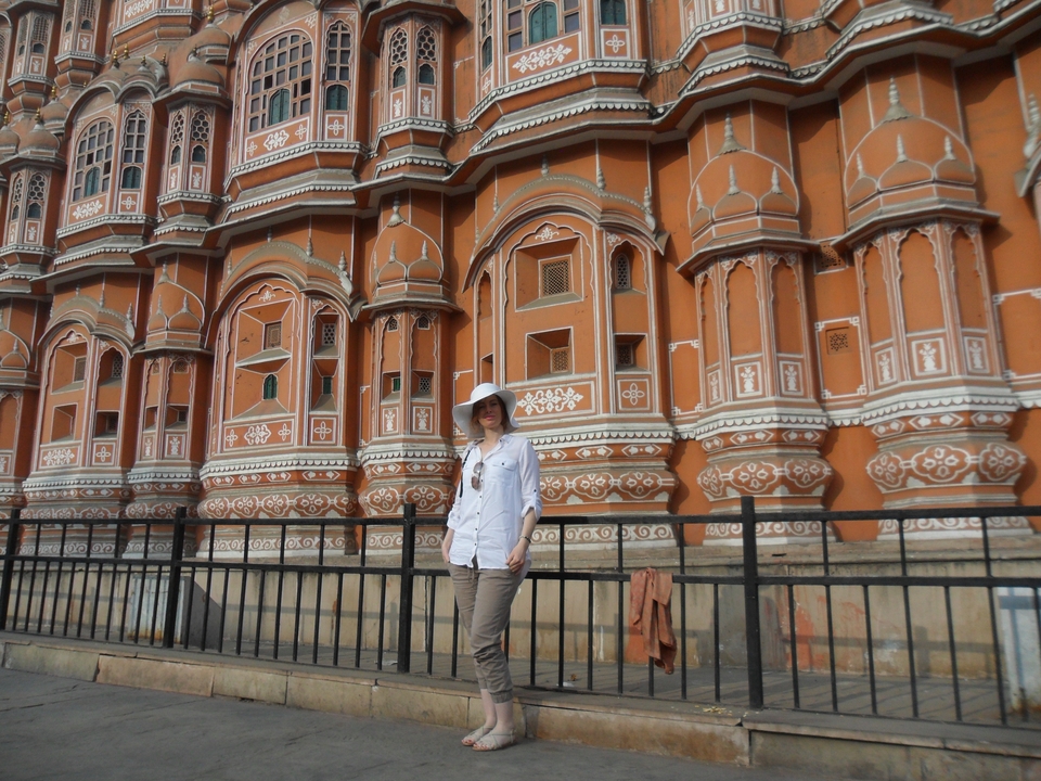 Traveler stands in front of the ornate pink façade of Hawa Mahal in Jaipur.