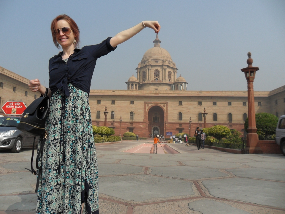 Woman posing playfully with the domed government building behind her in Delhi.