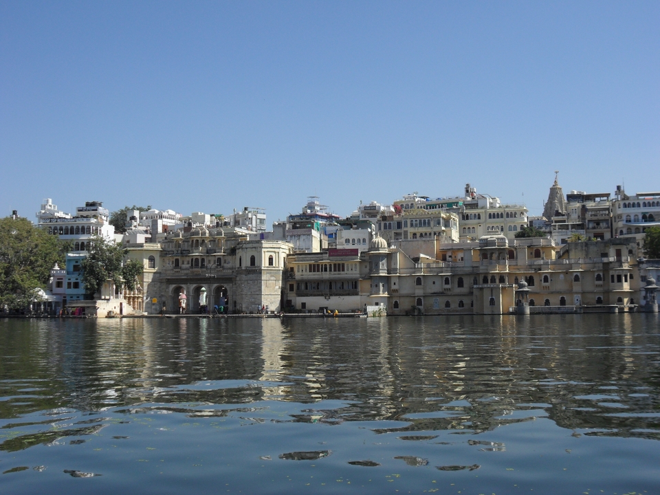 Historic waterfront palaces of Udaipur reflecting in calm lake waters.