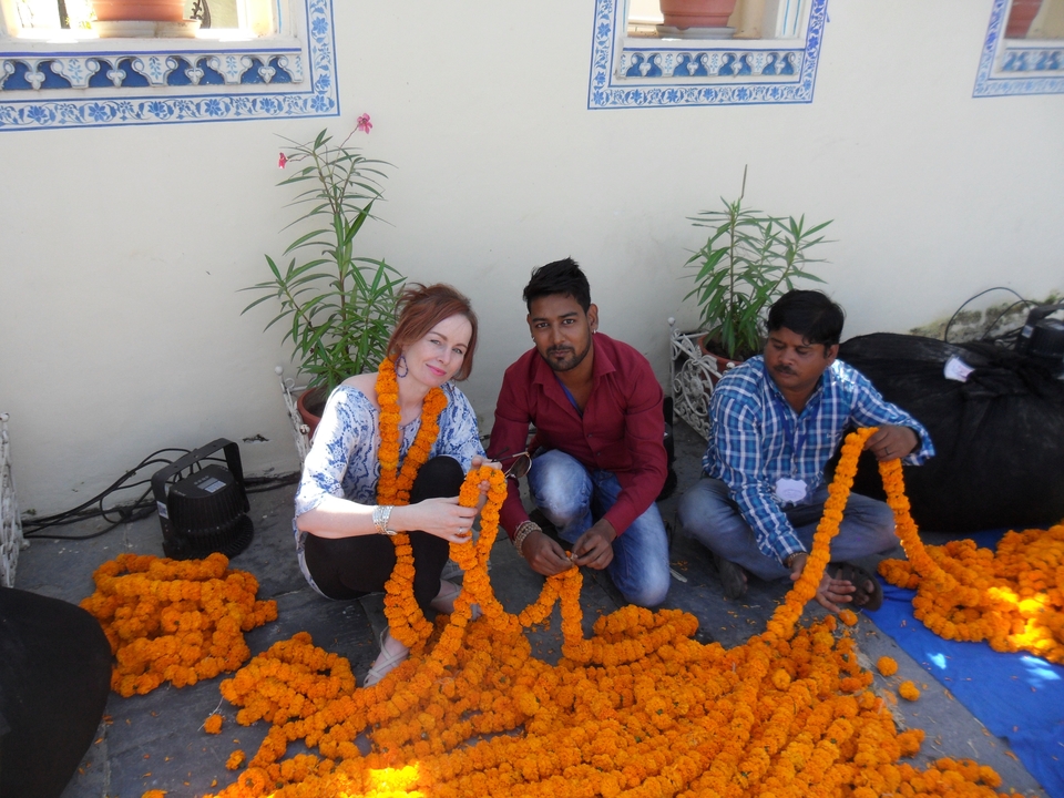 Traveler helps locals string bright orange marigold garlands.