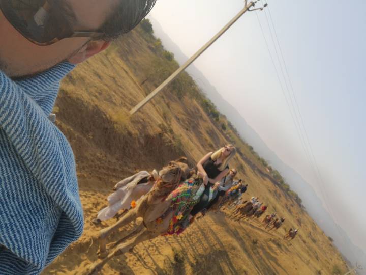 Des gens à dos de chameaux dans une zone désertique.