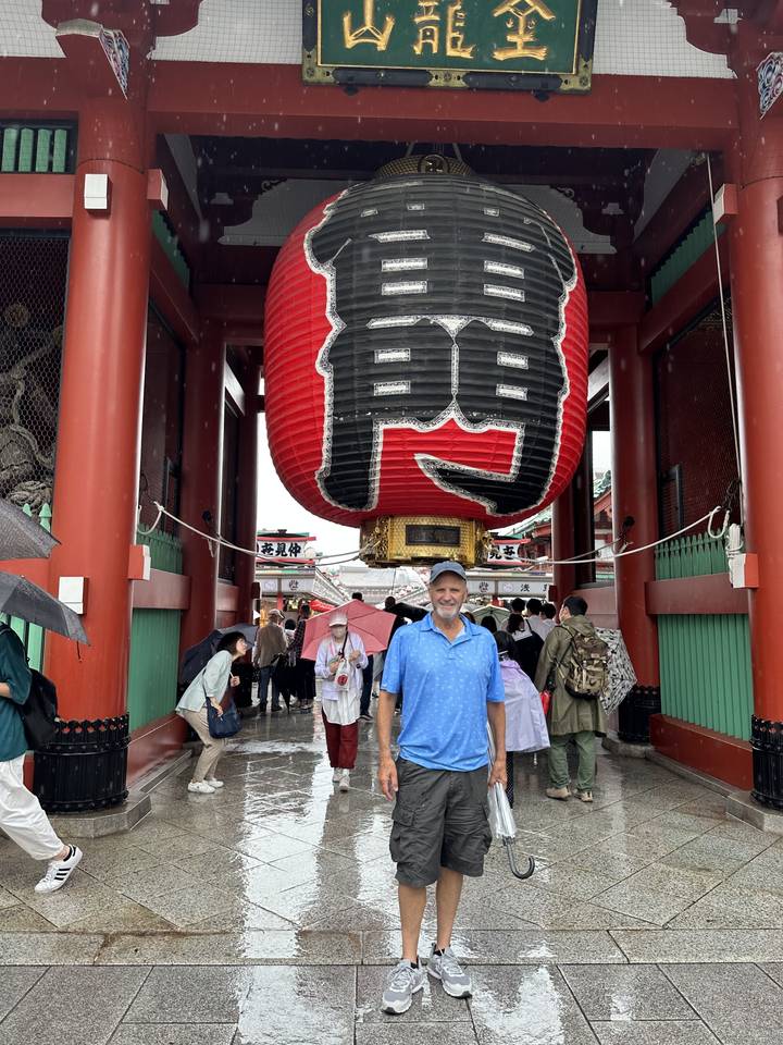 Une personne debout sous une grande lanterne japonaise traditionnelle.