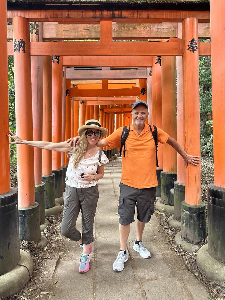 Deux personnes souriantes sous des torii orange traditionnels.