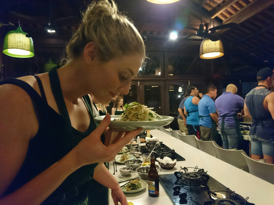 Personne dégustant un plat dans le cadre d'un cours de cuisine avec d'autres personnes en arrière-plan.