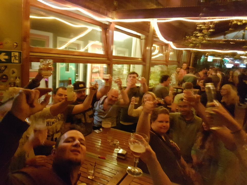 Groupe de personnes levant leur verre dans un bar, ambiance festive.