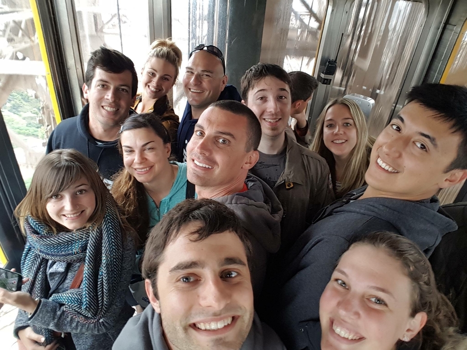 Groupe de personnes souriant dans un ascenseur ou un espace confiné.