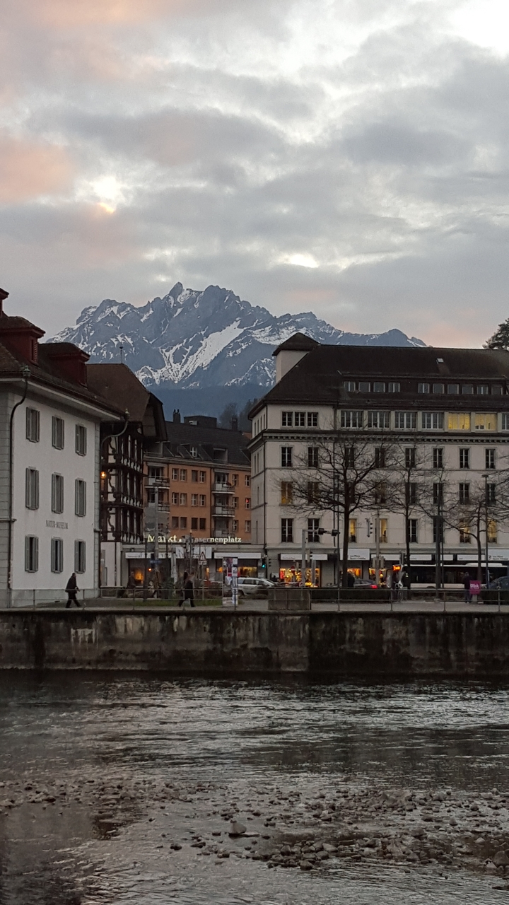 Rue avec bâtiments et montagne enneigée en arrière-plan.