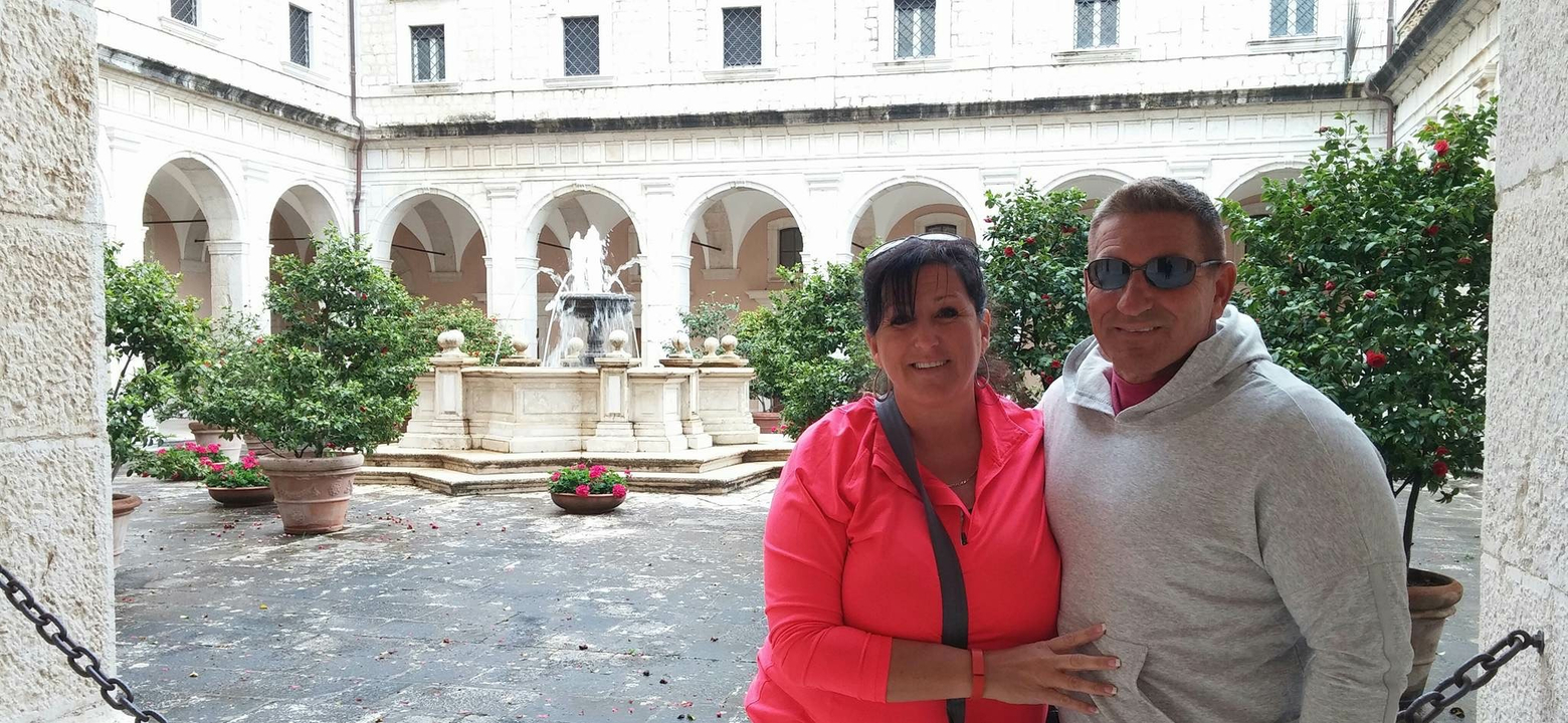 Deux personnes debout dans une cour avec une fontaine derrière elles.