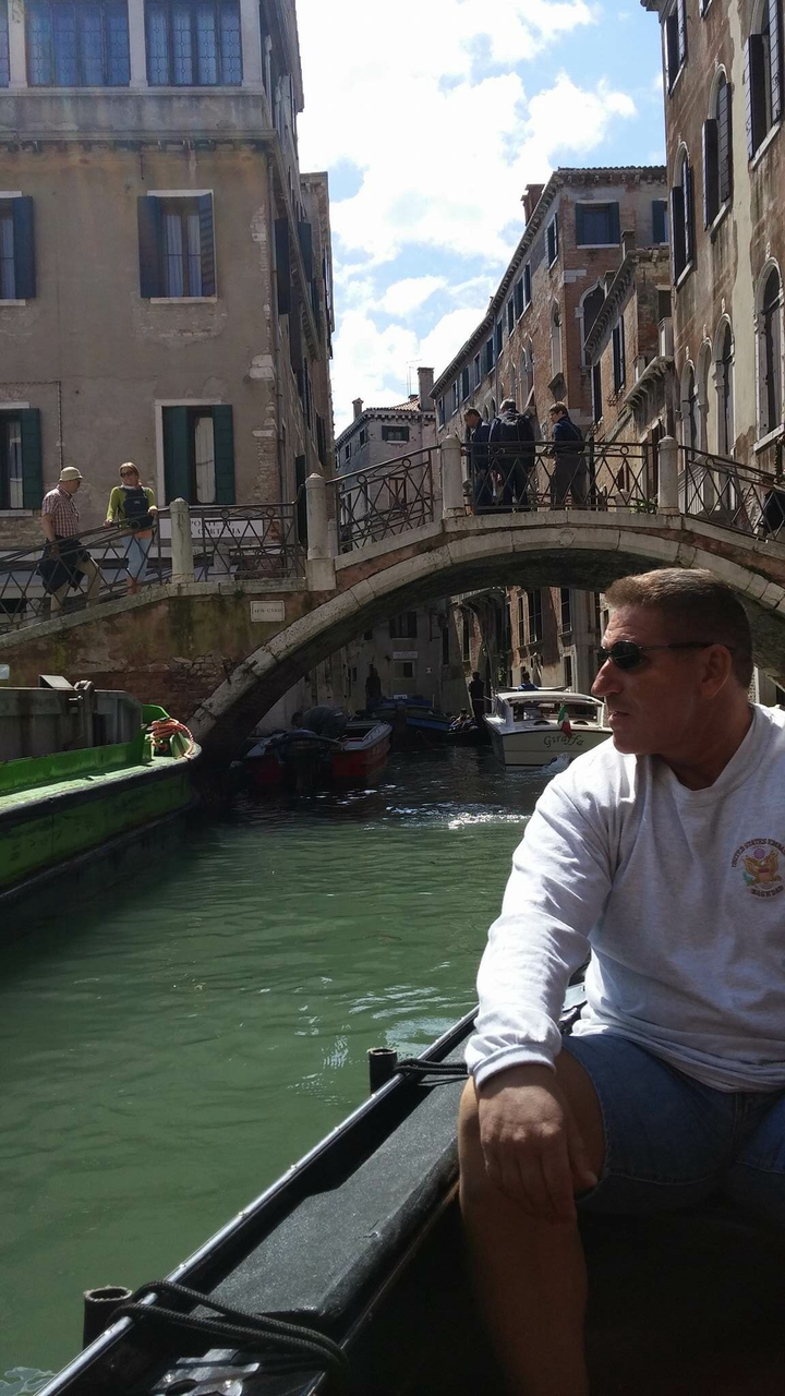 Personne assise dans un bateau sur un canal avec un pont au-dessus de la tête.