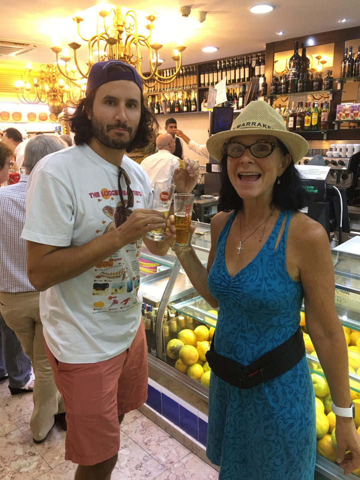 Deux personnes tenant des boissons à l'intérieur d'un étal de marché.