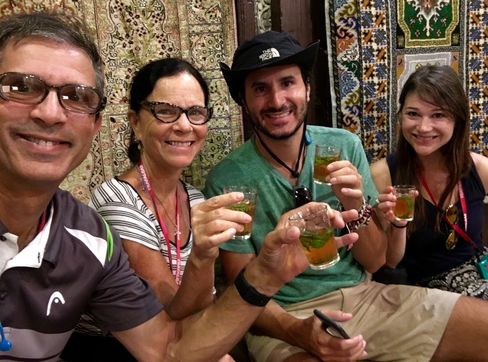 Groupe de personnes assises ensemble, tenant des verres contenant des boissons traditionnelles.