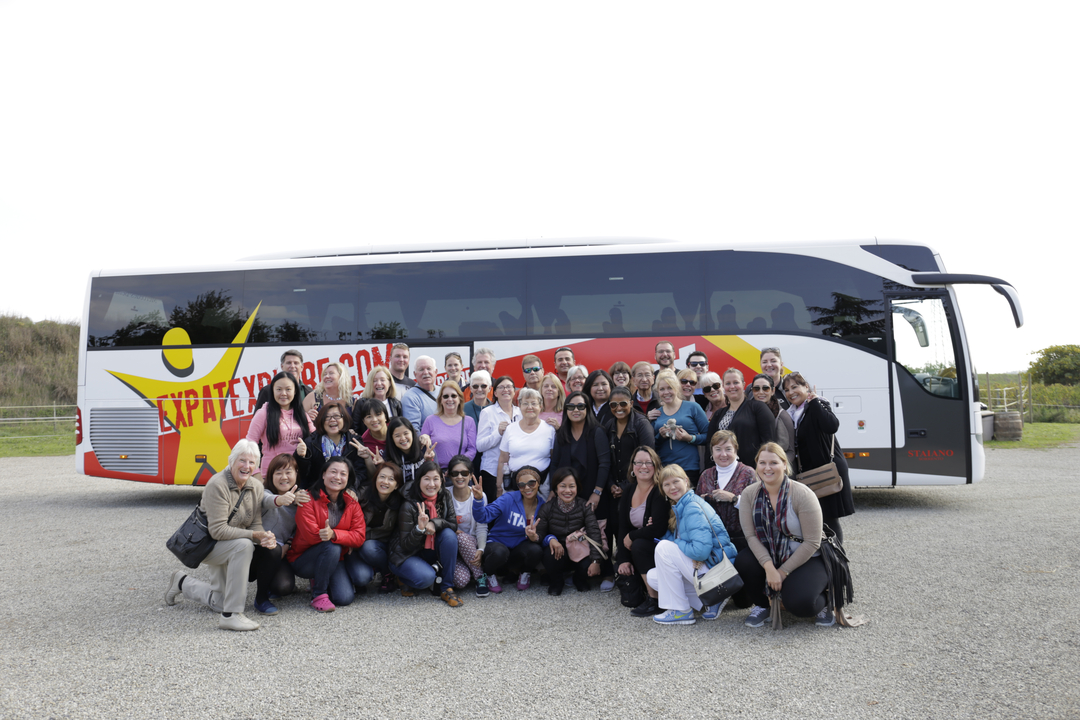 Grand groupe de personnes posant devant un bus de tourisme.