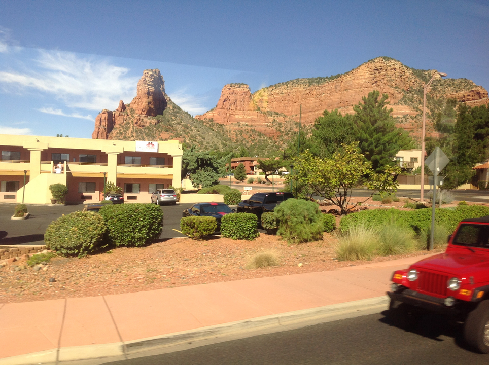 Paysage désertique avec des bâtiments et une jeep rouge.