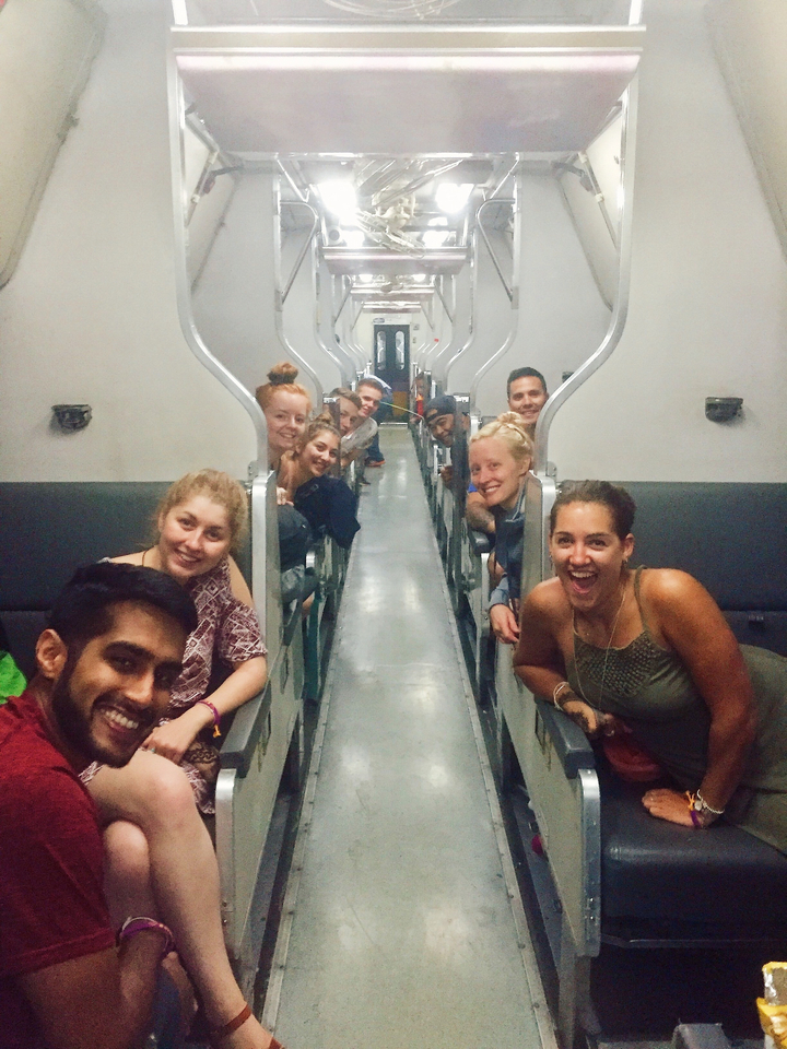 Group of people on a train, smiling and enjoying the ride.