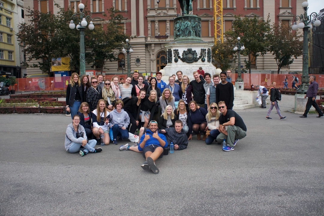 Photo de groupe devant un monument dans une zone urbaine.
