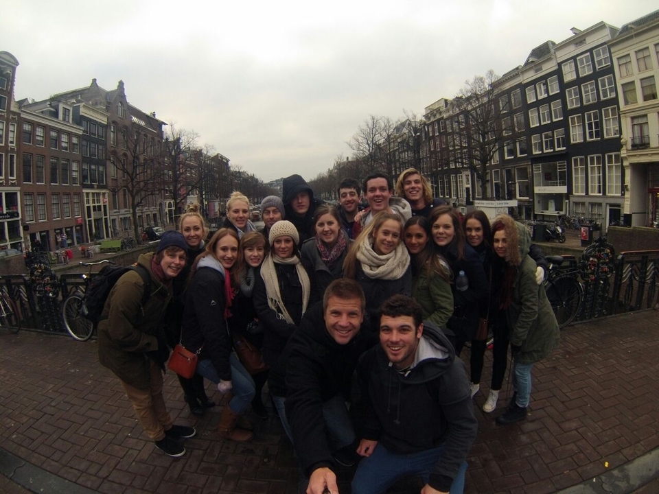 Group photo on a bridge with historic buildings in the background.