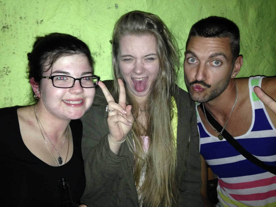 Trois personnes posant à l'intérieur, faisant des signes de paix et des grimaces.