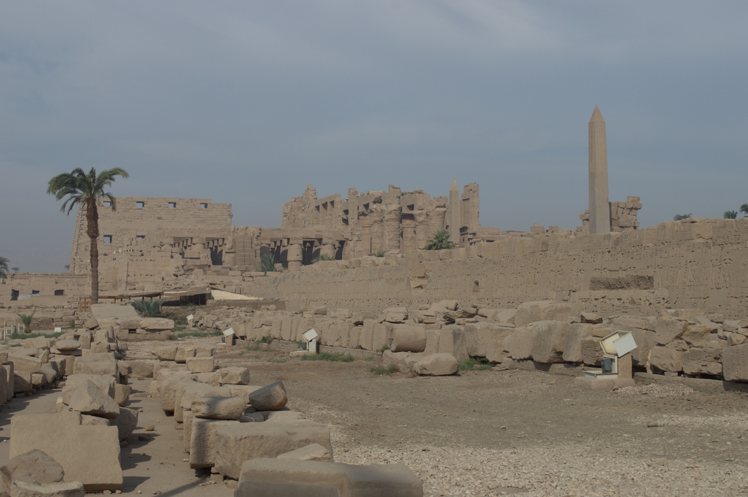 De grandes ruines anciennes avec des colonnes et un obélisque sous un ciel bleu.
