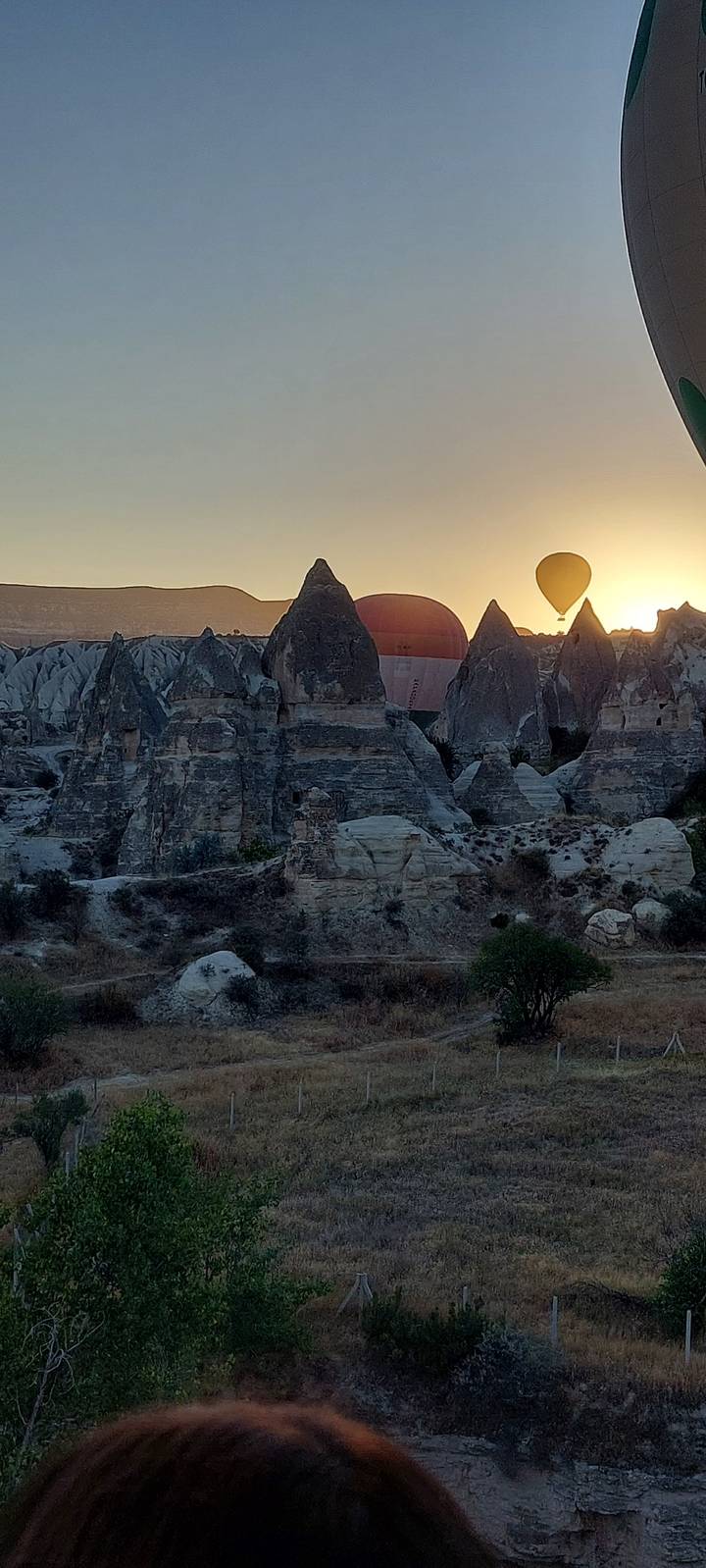 Montgolfières s'élevant au-dessus de formations rocheuses au lever du soleil.