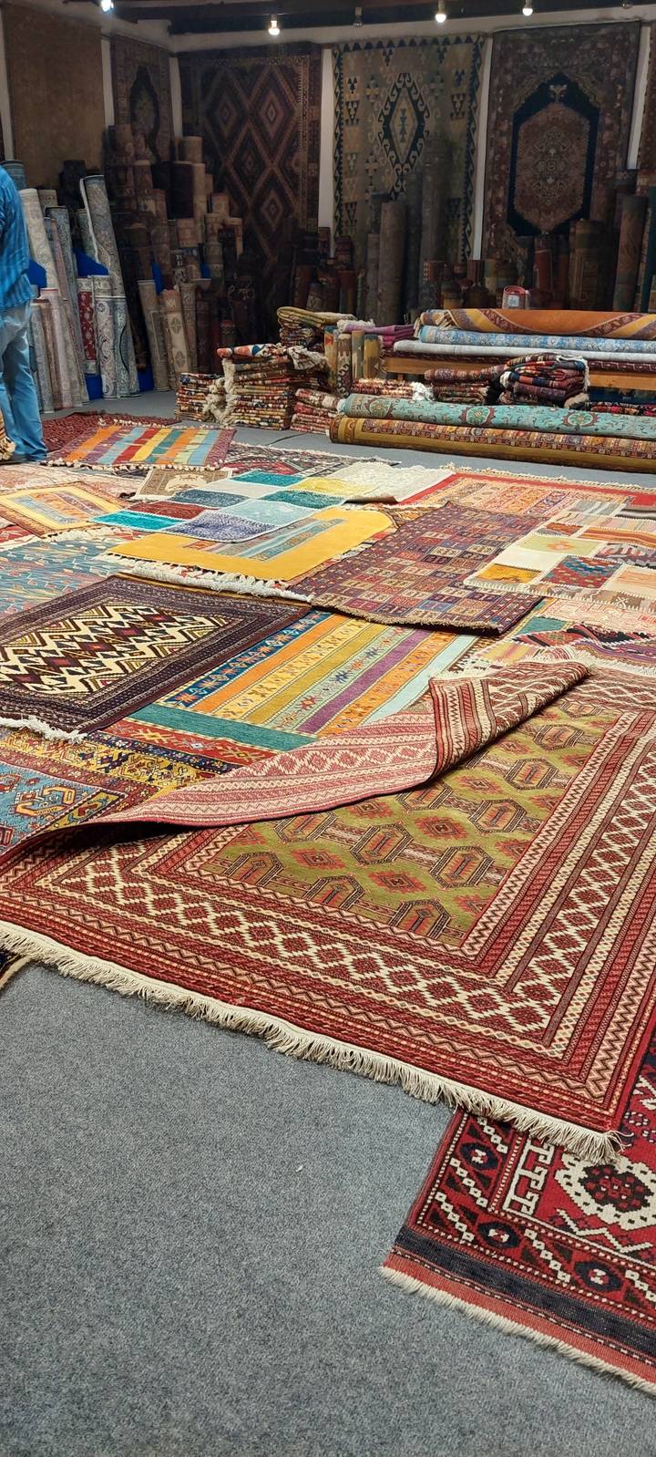Tapis tissés colorés exposés sur le sol.
