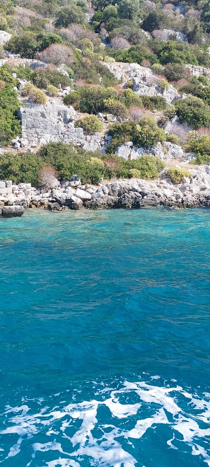 Vue aérienne d'une eau océanique bleu clair près d'un rivage rocheux.