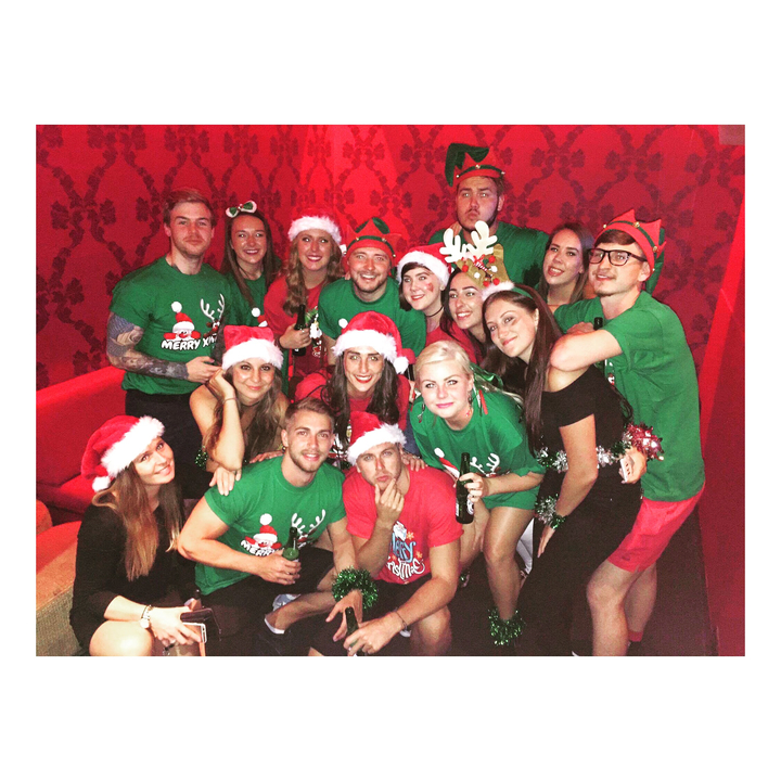 Group of people wearing Christmas themed clothing posing indoors.
