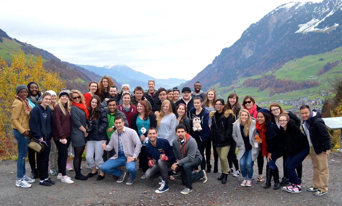 Grand groupe posant avec des montagnes en arrière-plan.
