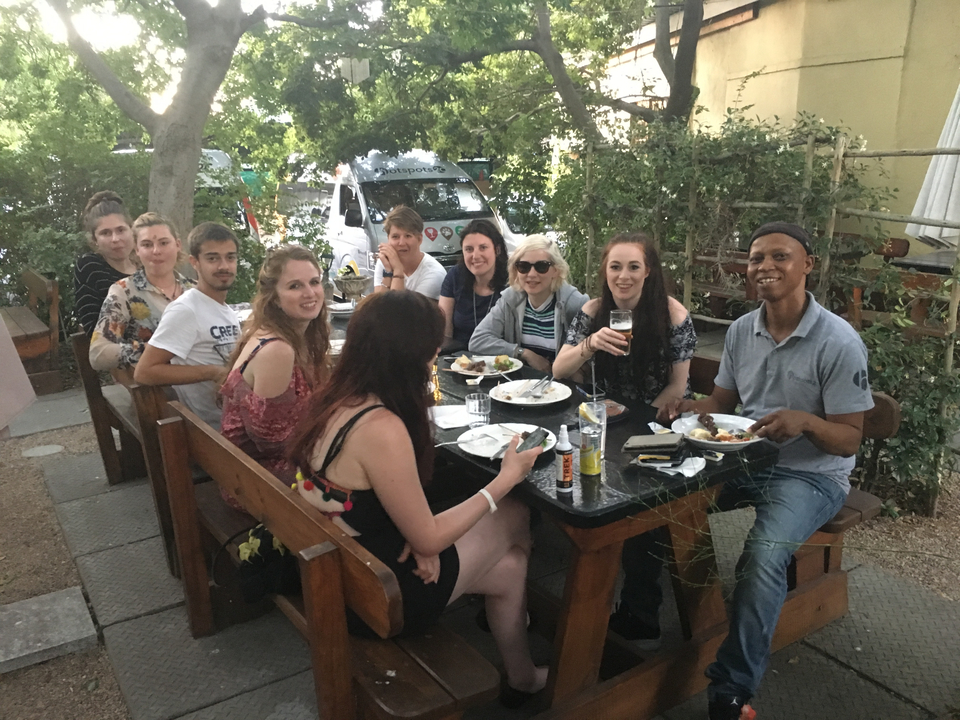 Groupe dînant en plein air autour d'une table en bois.
