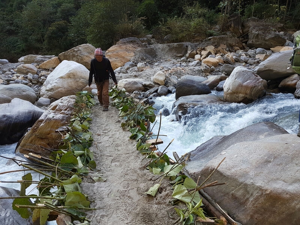 Personne marchant sur un pont de fortune au-dessus d'une rivière.