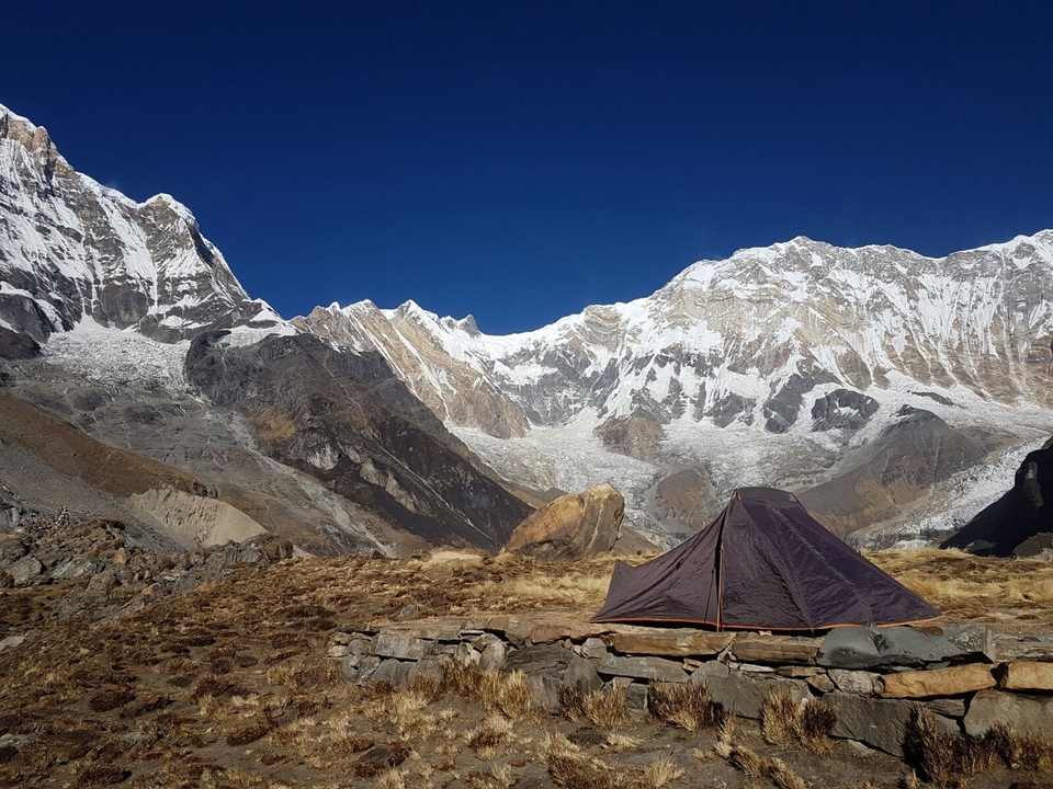 Tente installée dans les montagnes avec des sommets enneigés en arrière-plan.