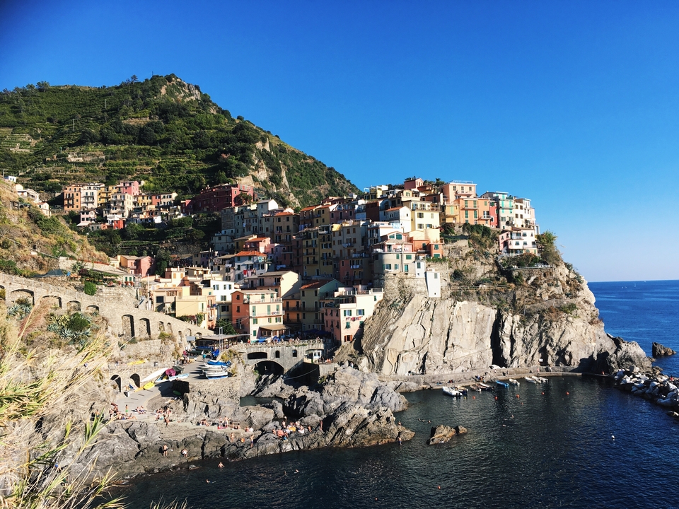 Village coloré sur une falaise au bord de la mer, ciel vibrant.