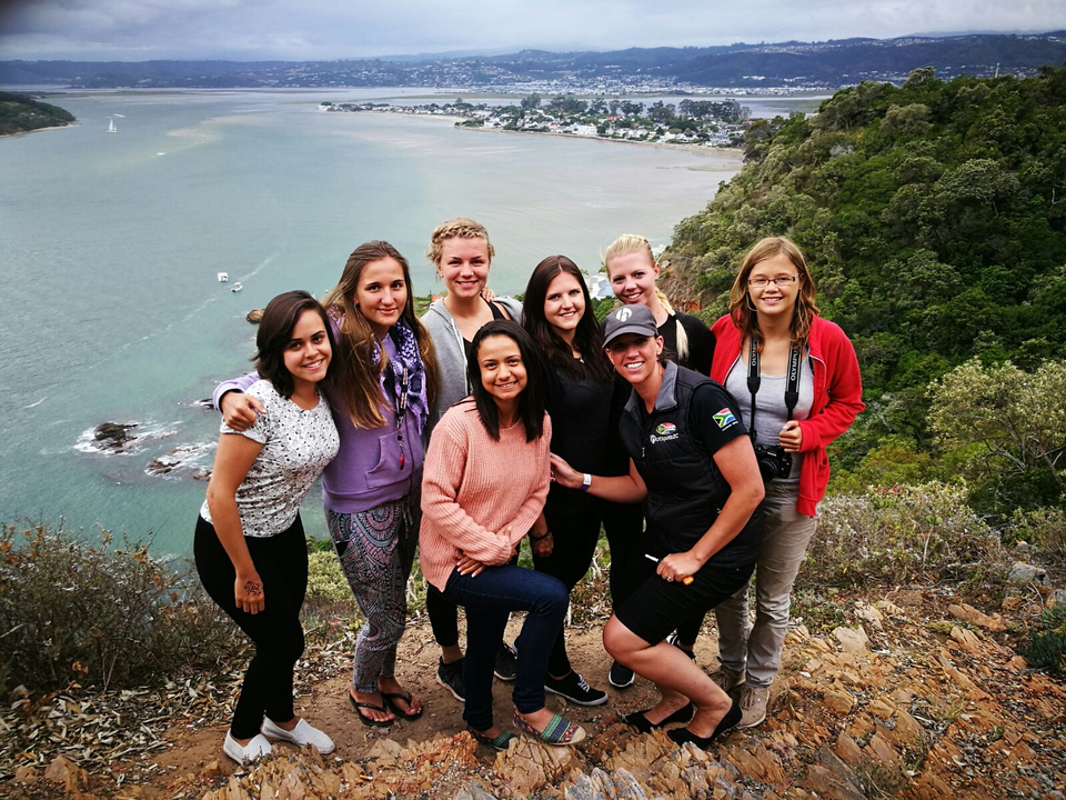 Un groupe de femmes posant sur un point de vue panoramique surplombant l'eau.