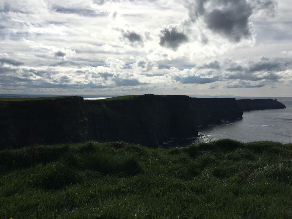 Falaises face à l'océan sous un ciel nuageux.