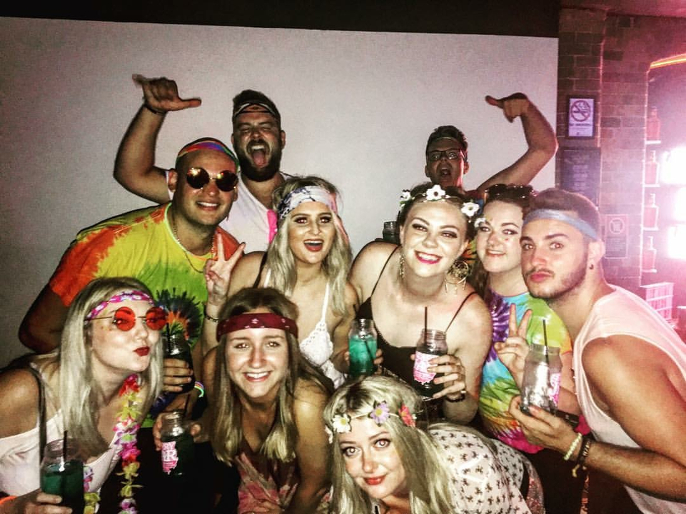A group of people smiling and posing with drinks.