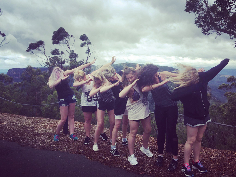Group of young people striking poses in a scenic landscape.