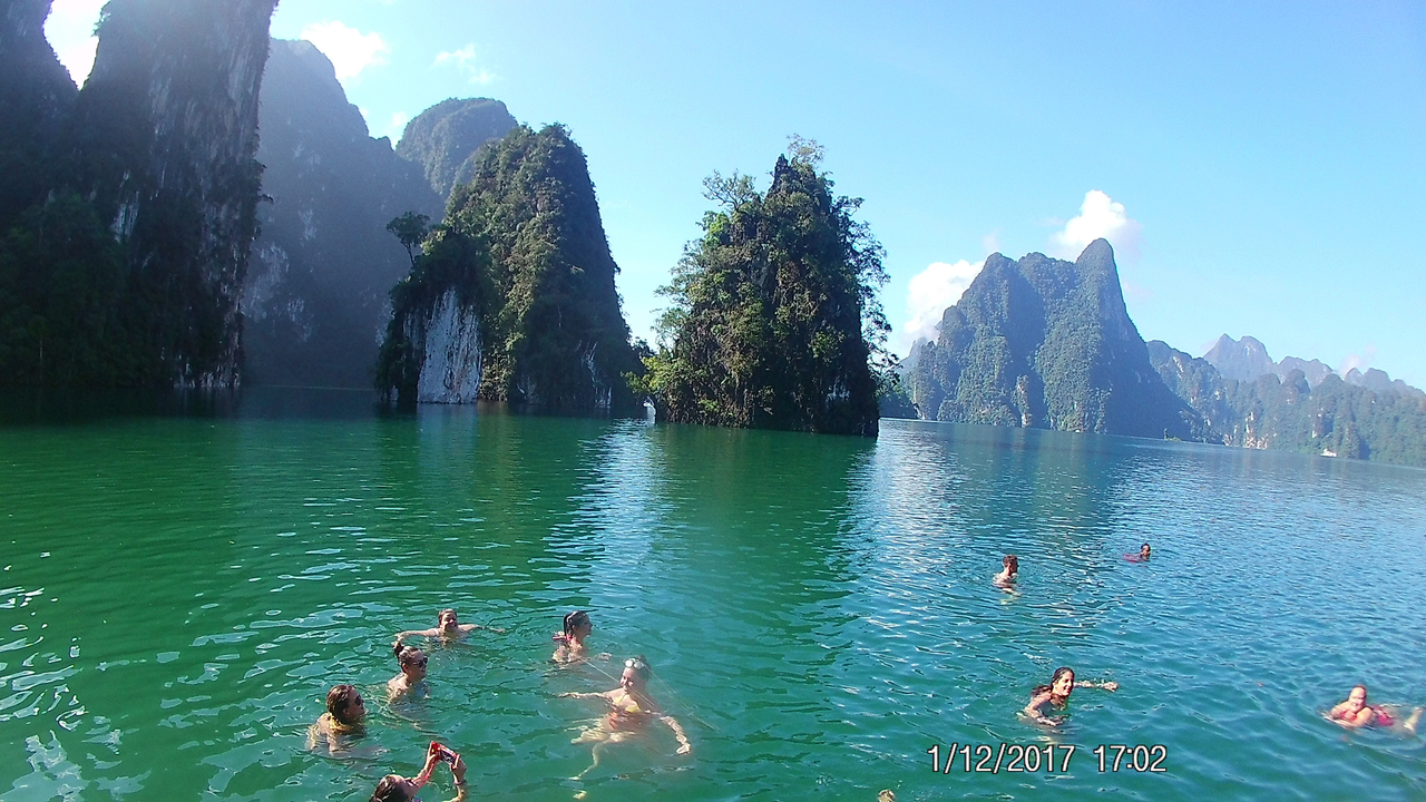 People swimming in a lake surrounded by tall cliffs.