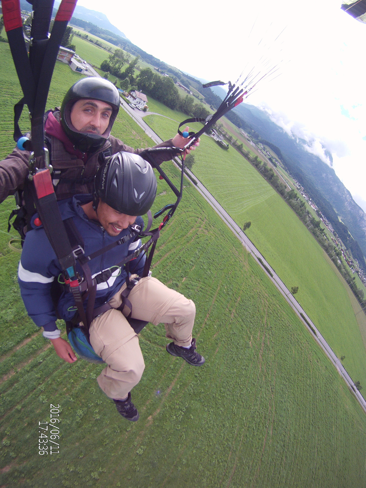 Des personnes font du parapente au-dessus d'un paysage verdoyant.