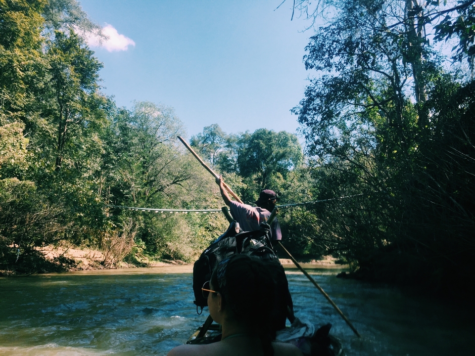 Personne pagayant dans un bateau sur une rivière bordée de forêts.