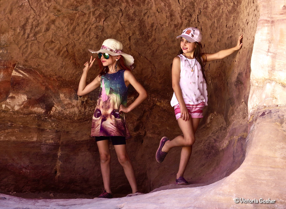 Two children posing against a rocky background.